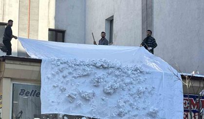 Vatandaşlar çatıdaki kar kütlelerini brandayla indirdi